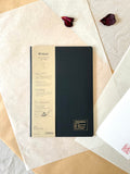 Kleid 2mm grid notes A5 black notebook showing full cover beside Aya stamp on washi paper