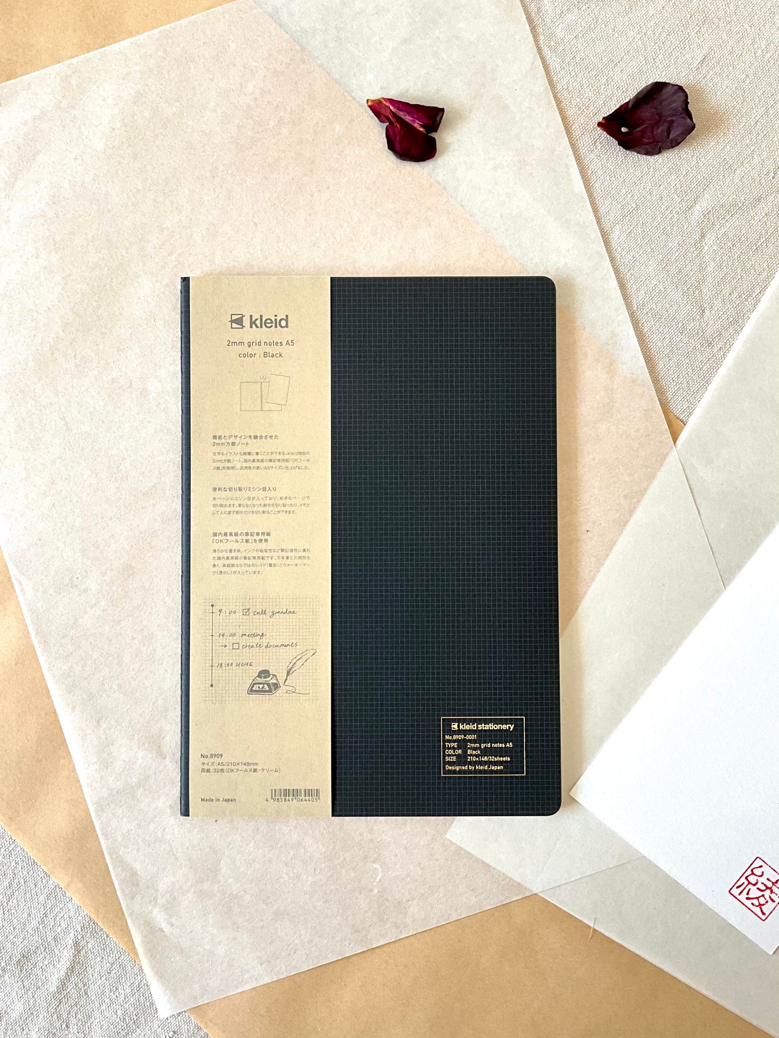 Kleid 2mm grid notes A5 black notebook showing full cover beside Aya stamp on washi paper