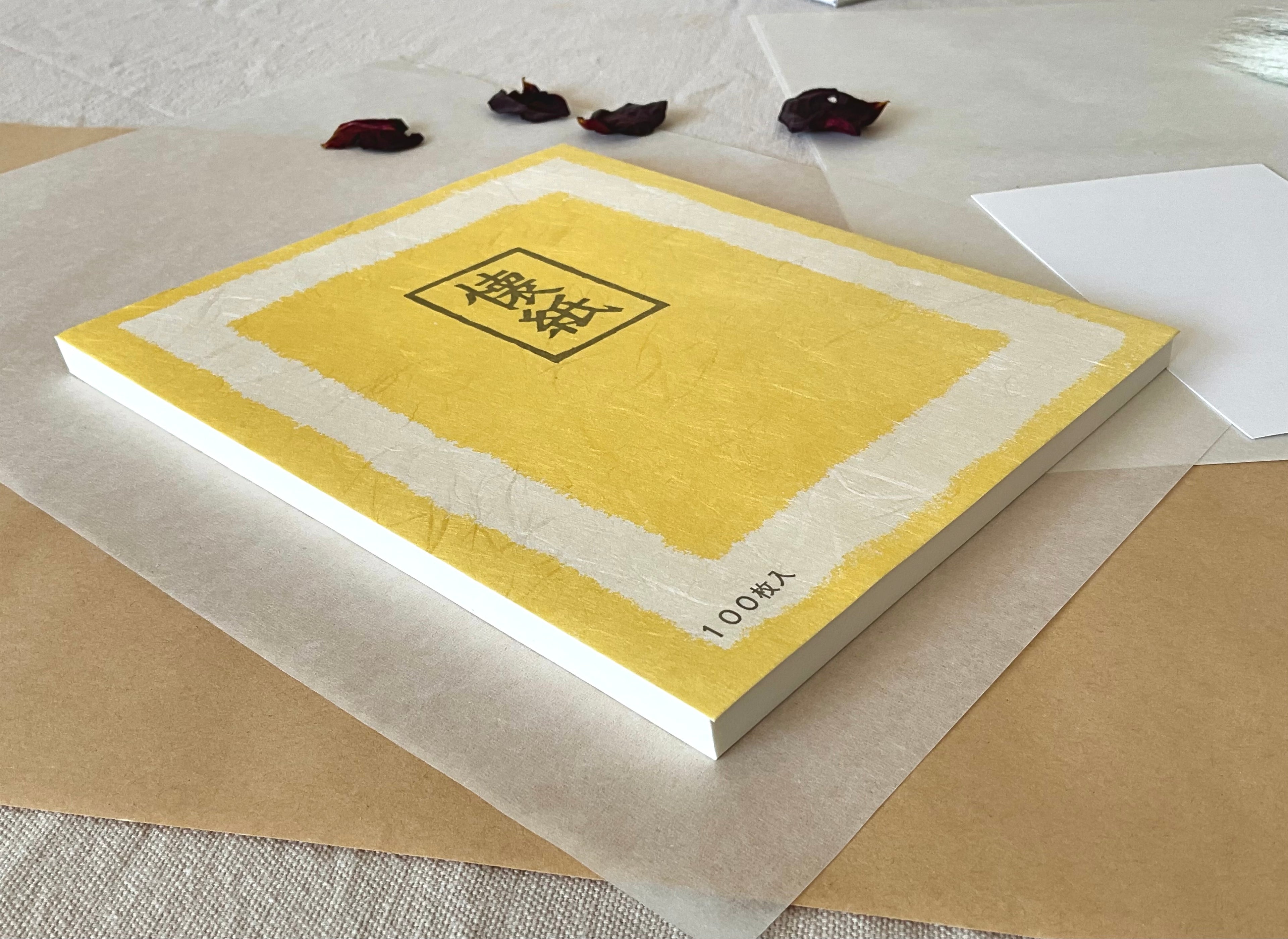 Morita Washi kaishi tea ceremony paper pack flat on neutral background, yellow washi cover with brushed border design and framed kaishi kanji, text reading 100 sheets, with hanko stamp card visible