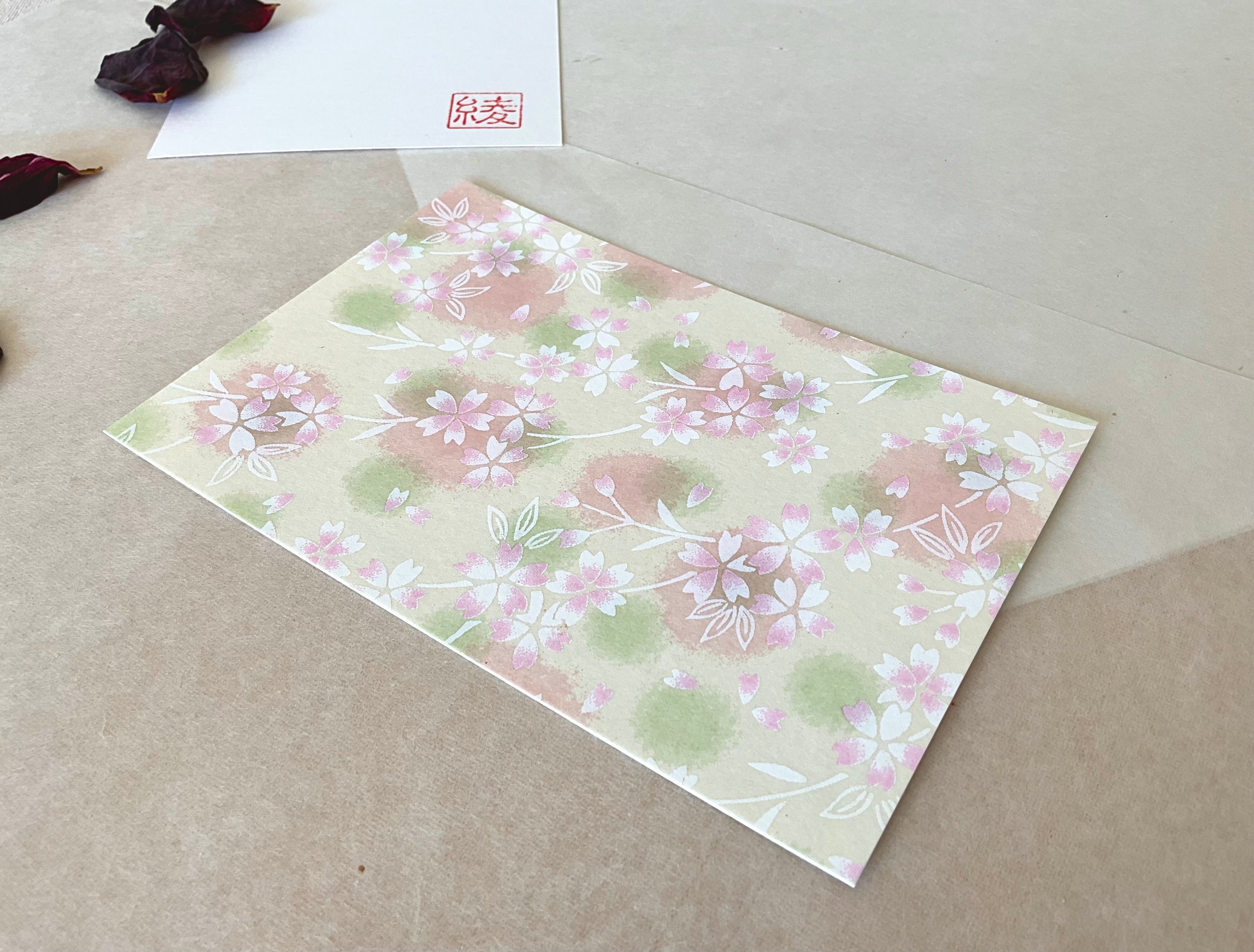 Morita Washi sakura scatter postcard angled on layered paper showing delicate floral pattern detail
