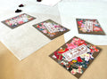 Four packs of Morita Washi yuzen flower shaped stickers arranged at angles on layered washi and kraft paper, each pack showing a different assortment of colorful chiyogami petal cut stickers bursting out of brown card backing, with dried rose petals and hanko stamp card
