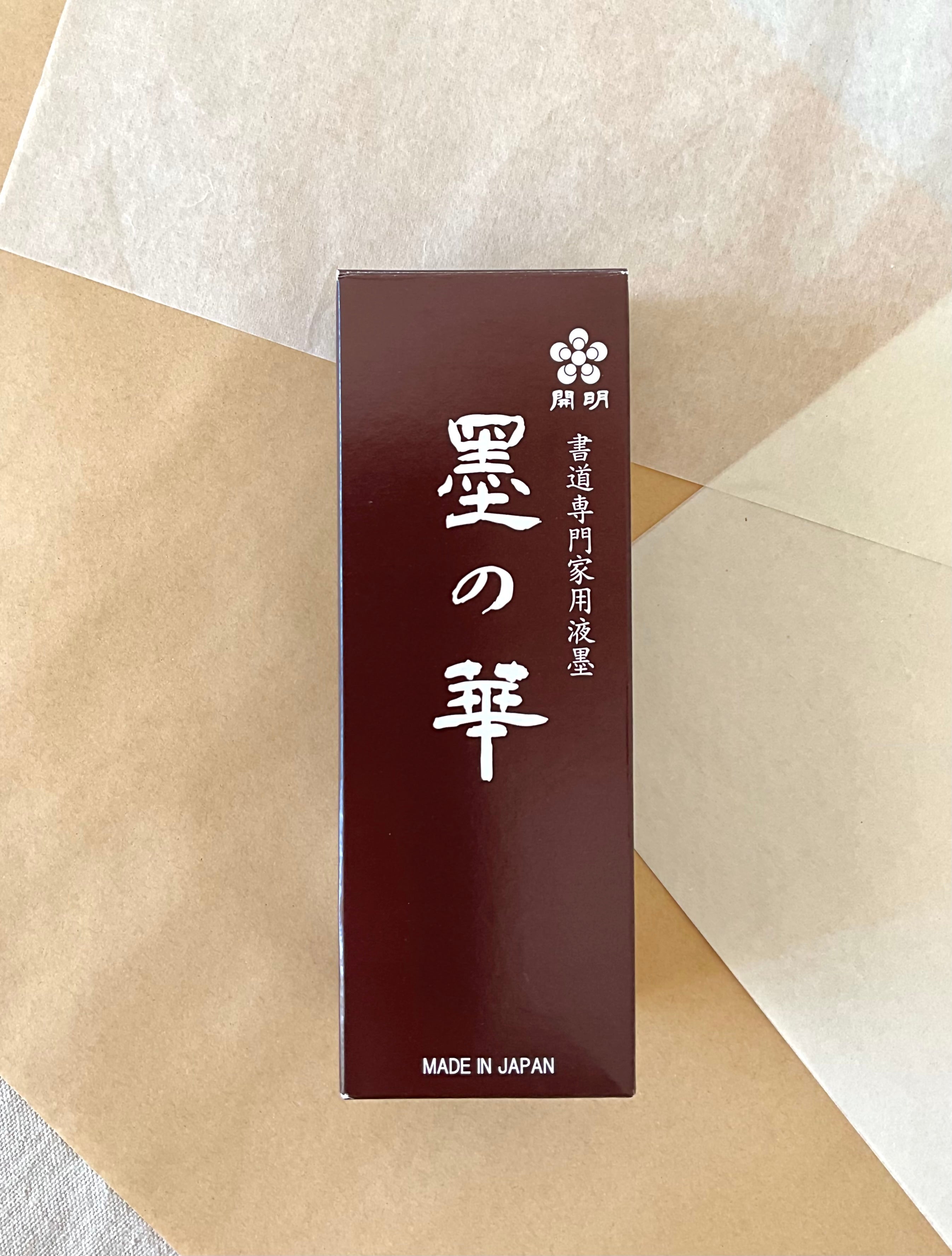Kaimei Sumi no Hana liquid ink bottle in dark red presentation box on layered washi paper background