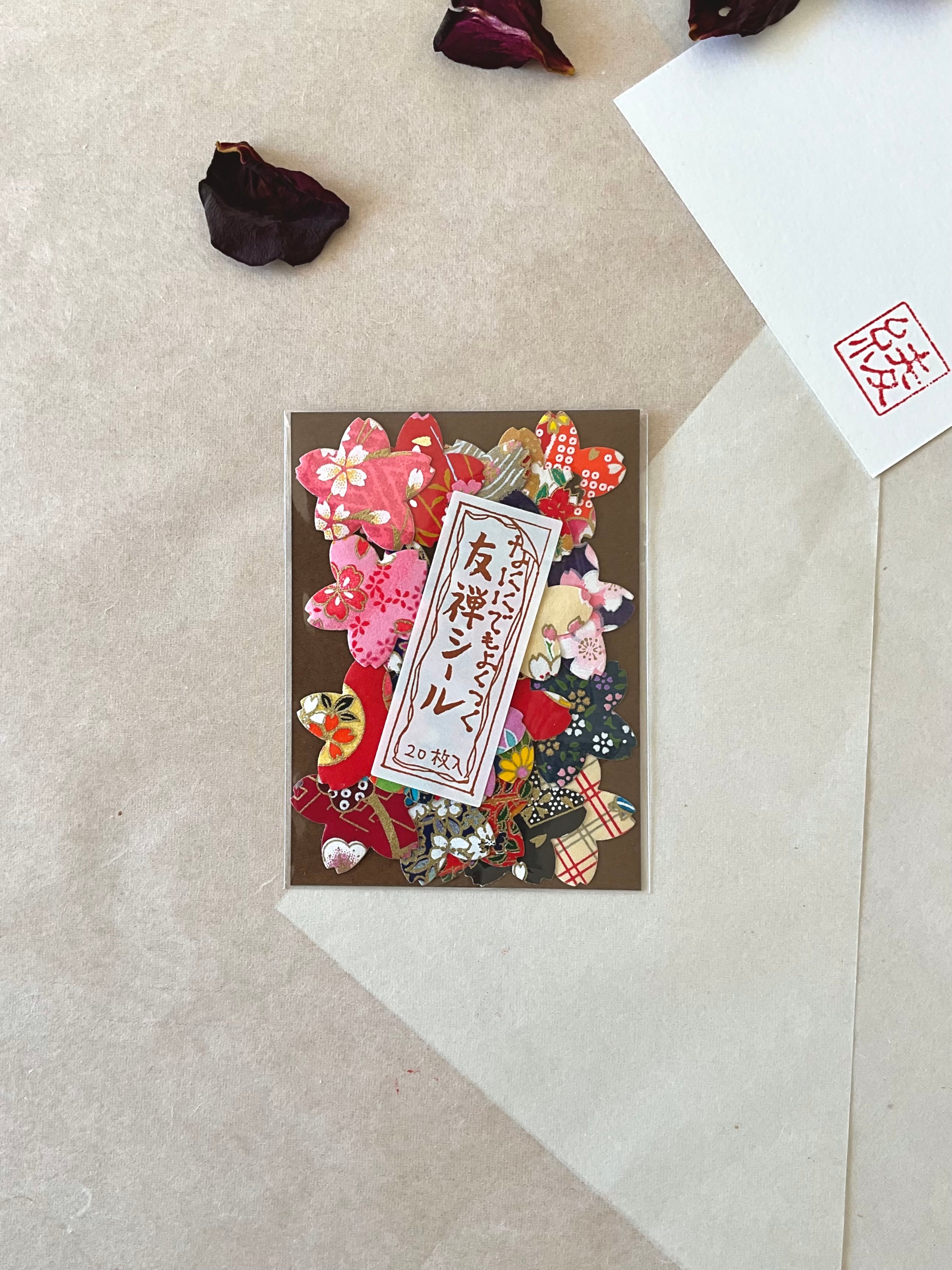 Morita Washi yuzen flower shaped sticker pack on washi background, warm tones emphasizing pink sakura, red floral and soft chiyogami petal shapes, Japanese label centered, with dried rose petals and hanko stamp card