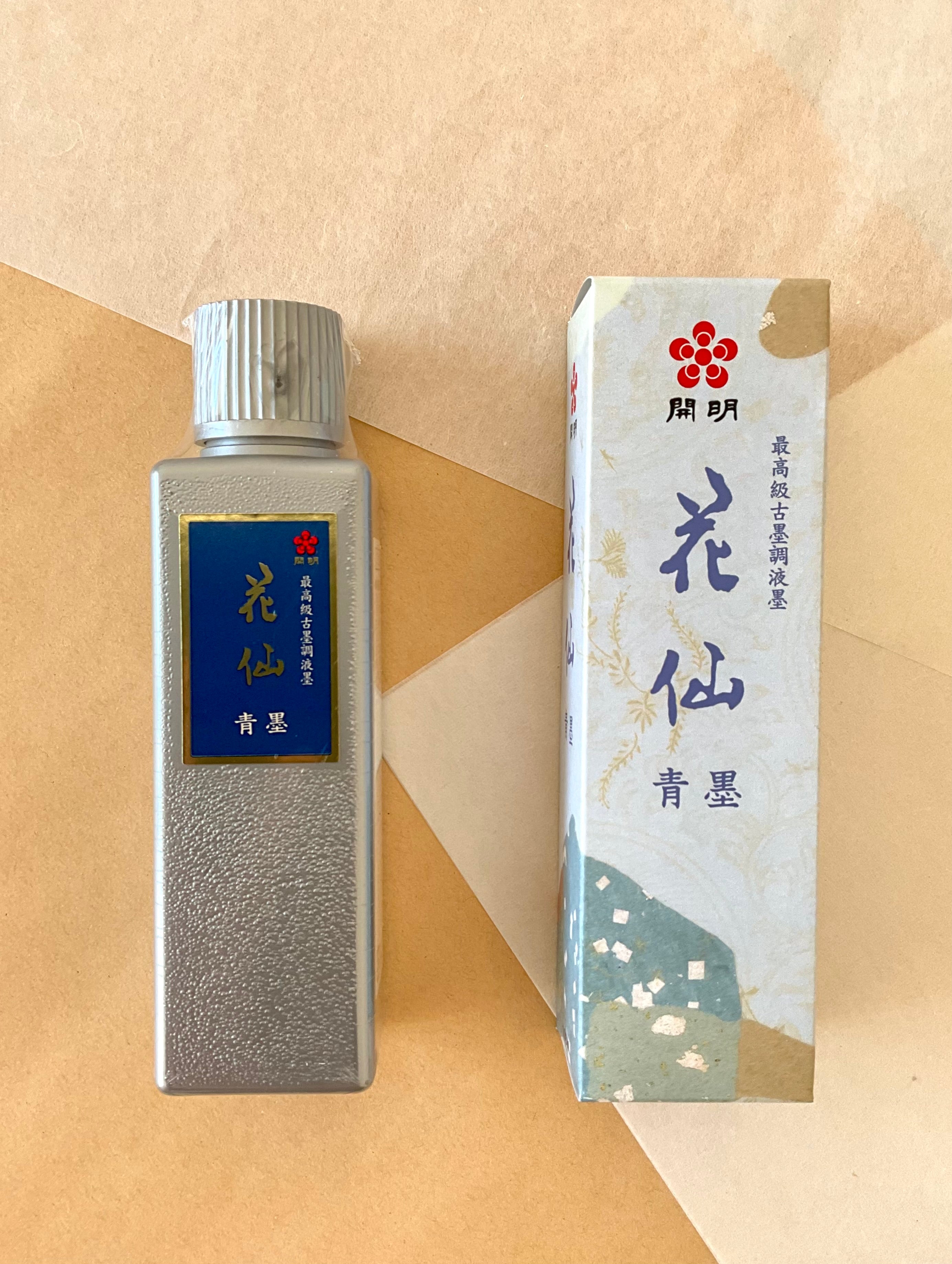 Kaimei Kasen Seiboku blue-black ink bottle and box side by side on layered paper background