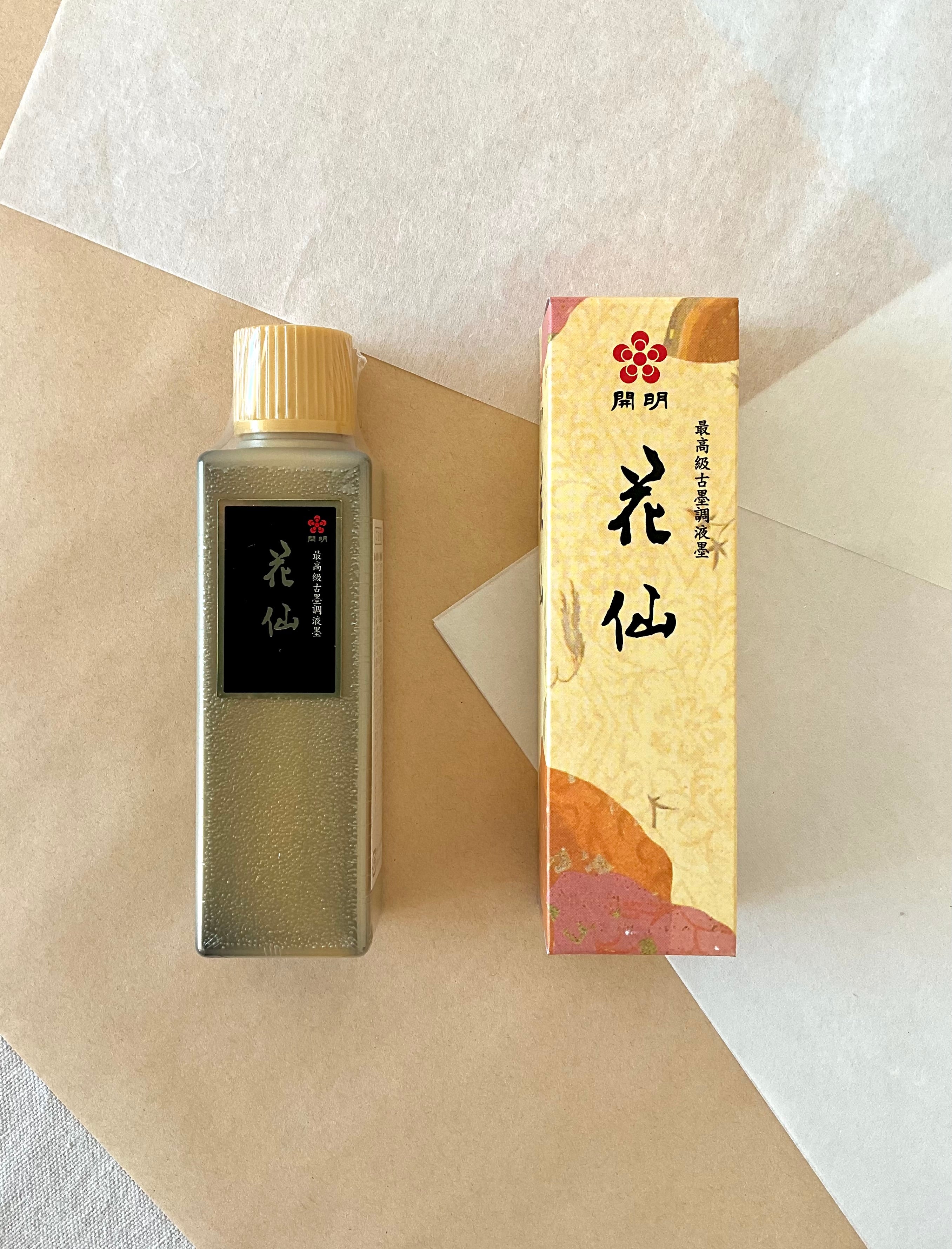 Kaimei Kasen black ink bottle and gold box side by side on layered washi and kraft paper