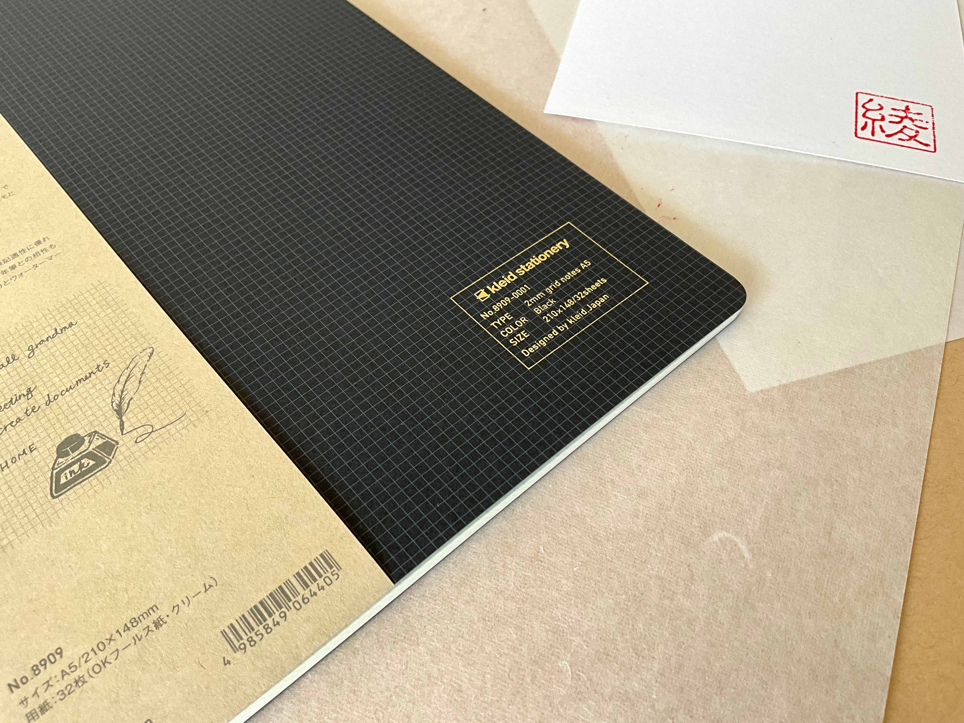 Kleid A5 black notebook corner showing gold foil specifications label and 2mm grid cover texture
