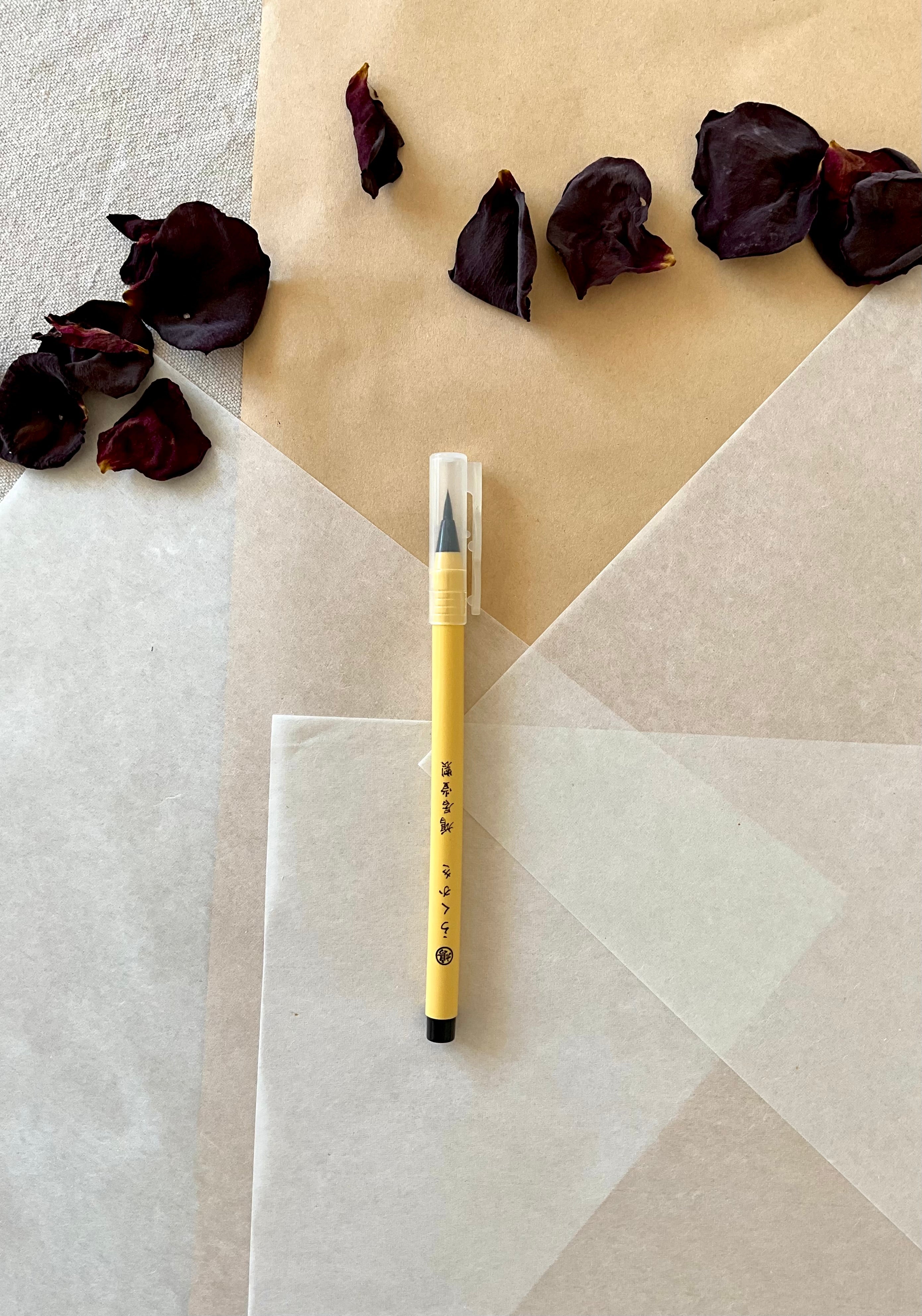 Kyukyodo Rakuka yellow calligraphy brush pen upright on layered washi paper with dried rose petals