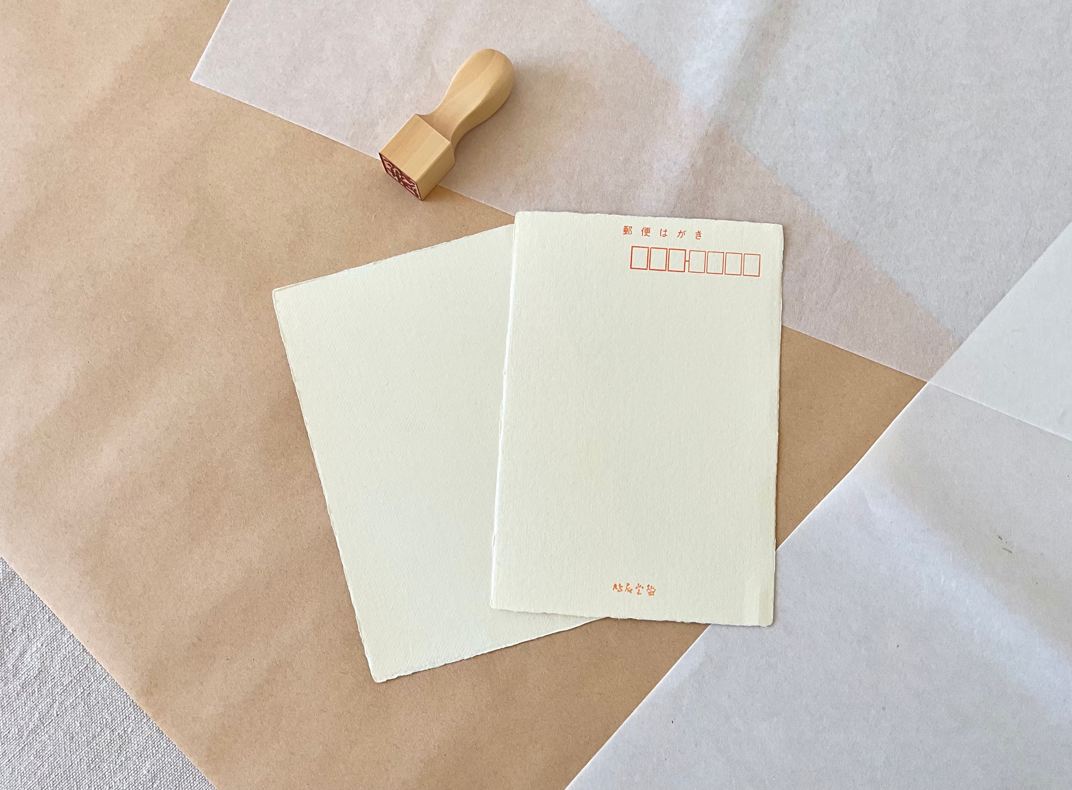 Two yellow handmade Kyukyodo washi postcards showing natural deckled edges on kraft paper background
