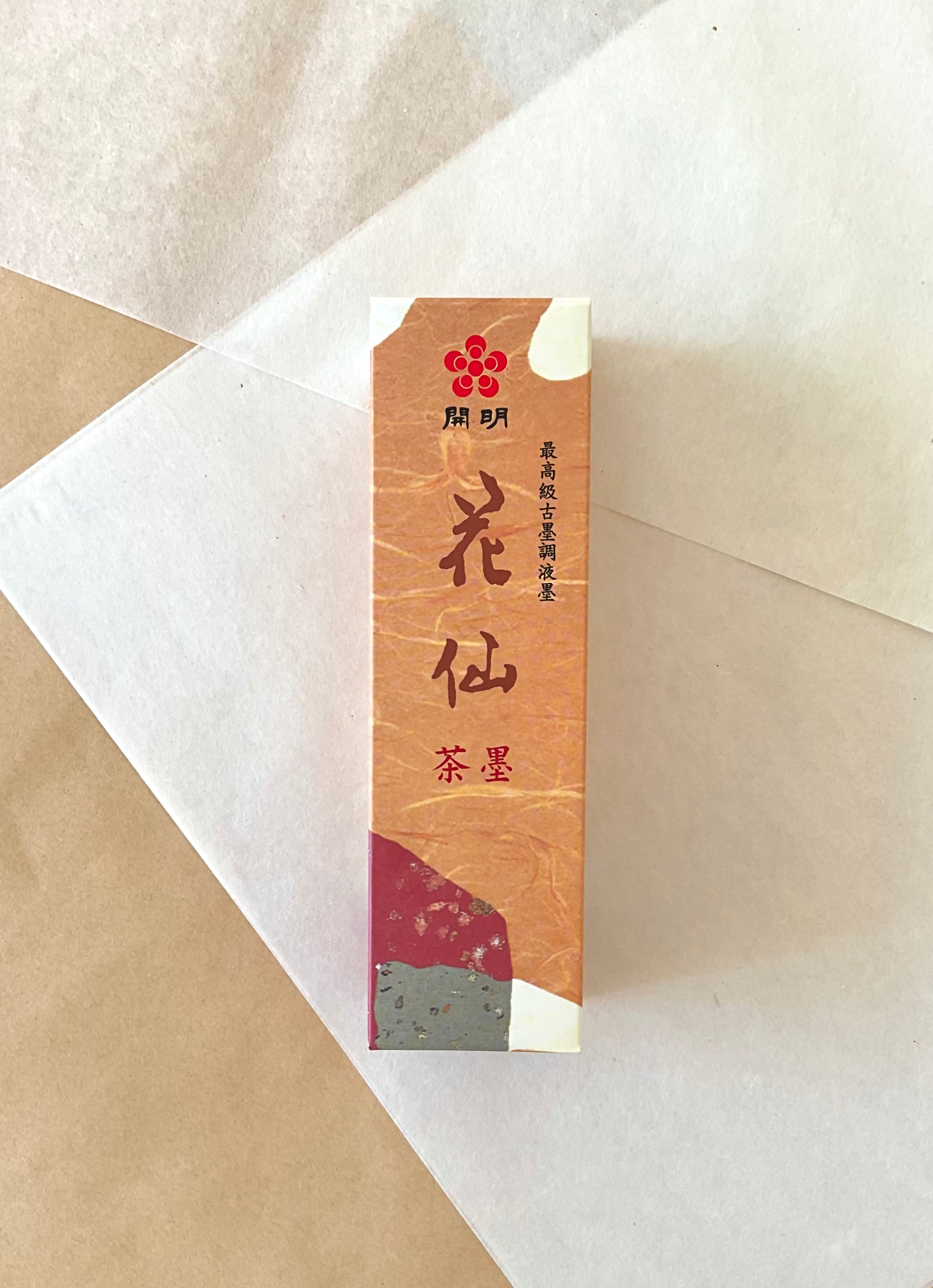 Kaimei Kasen Chaboku brown-black liquid ink in warm orange presentation box on layered washi paper
