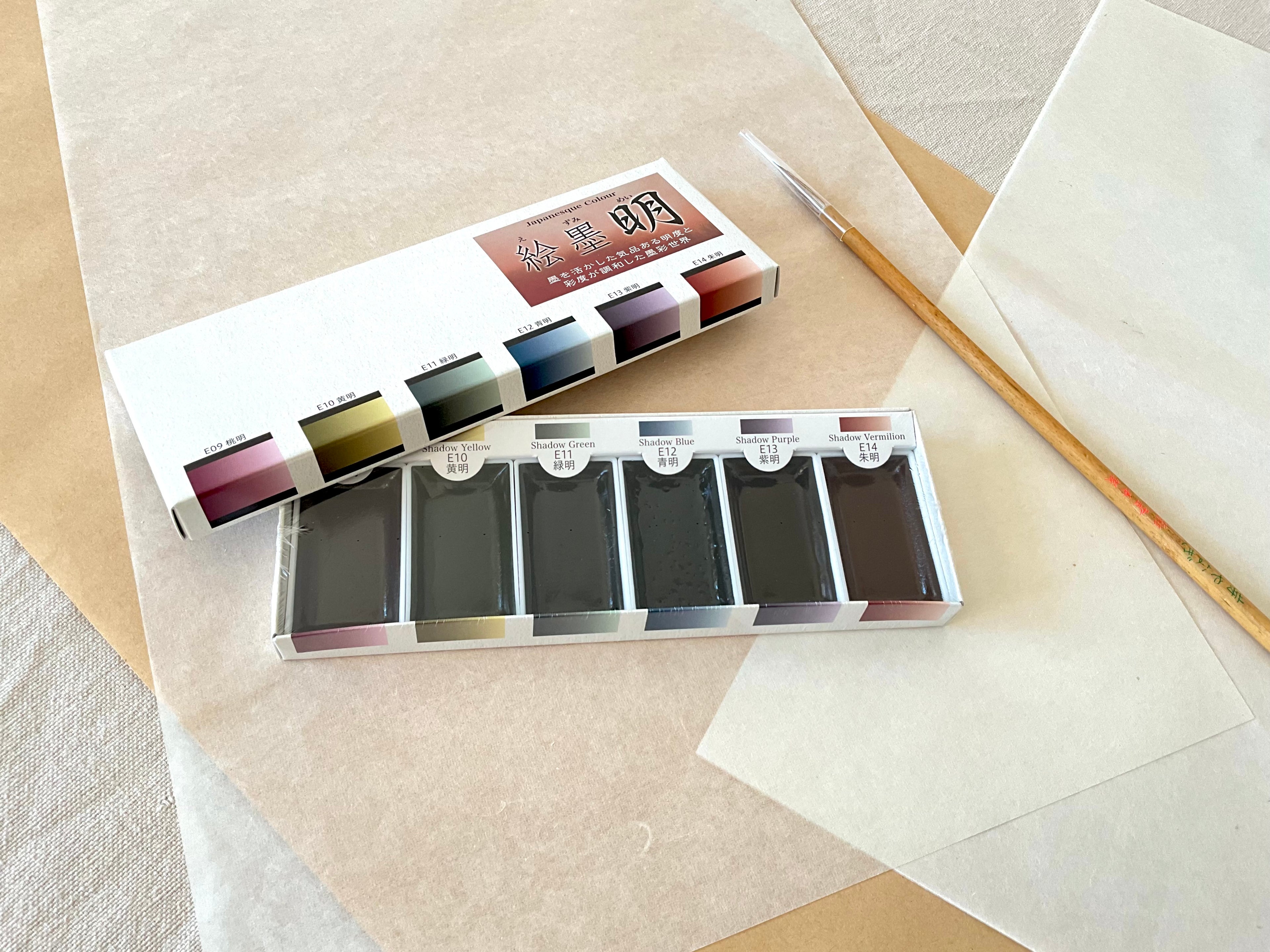 Ezumi Mei set open showing six shadow color watercolor pans with calligraphy brush on washi paper